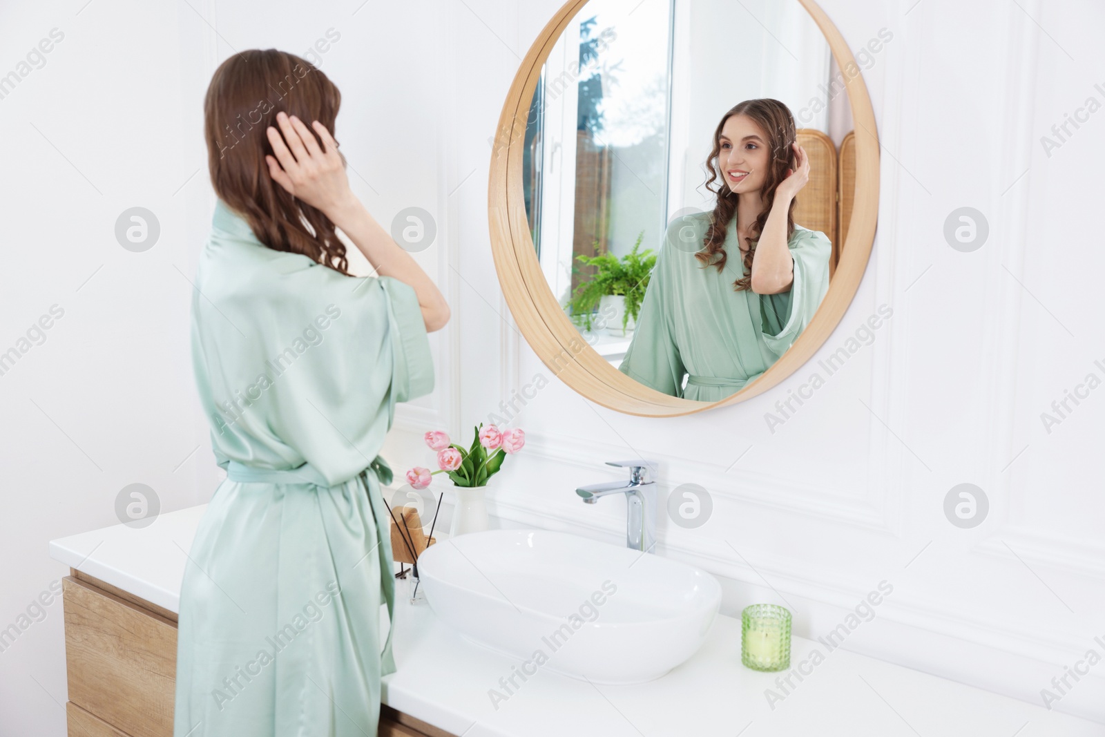 Beautiful woman looking at herself in mirror indoors Photo of Beautiful woman looking at herself in mirror indoors