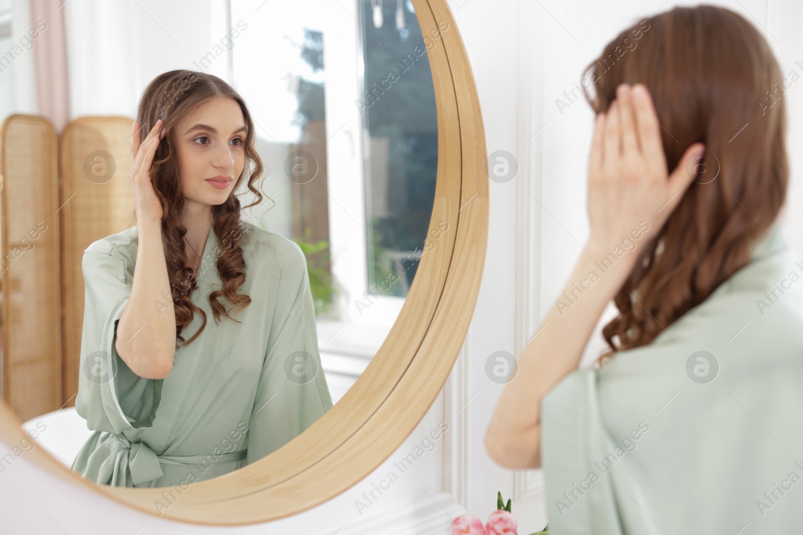 Beautiful woman looking at herself in mirror indoors Photo of Beautiful woman looking at herself in mirror indoors