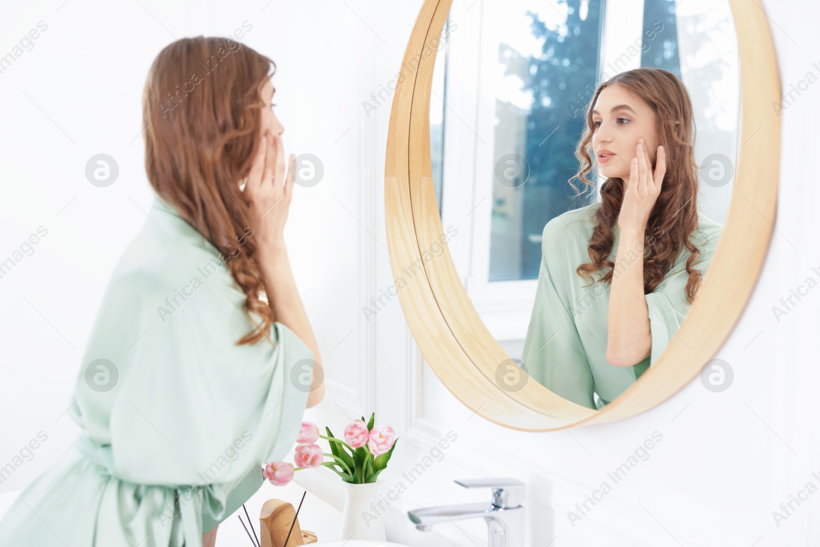 Beautiful woman looking at herself in mirror indoors Photo of Beautiful woman looking at herself in mirror indoors