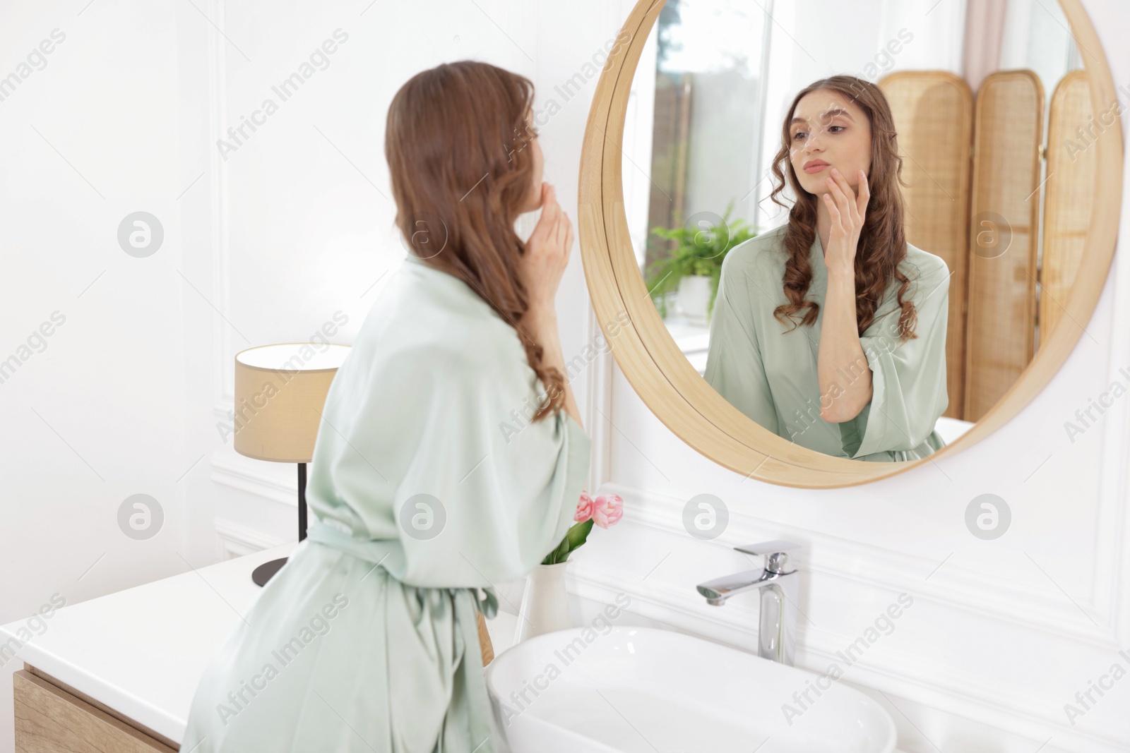 Beautiful woman looking at herself in mirror indoors Photo of Beautiful woman looking at herself in mirror indoors