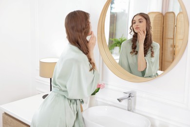 Photo of Beautiful woman looking at herself in mirror indoors