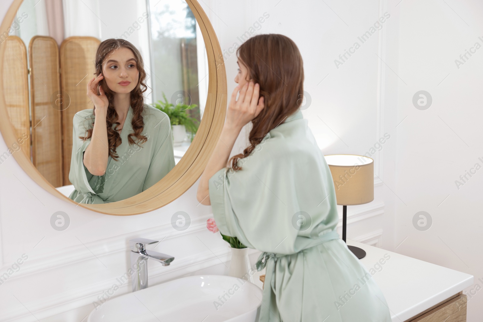 Beautiful woman looking at herself in mirror indoors Photo of Beautiful woman looking at herself in mirror indoors