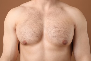 Photo of Young man with hairy chest on brown background, closeup. Epilation procedure