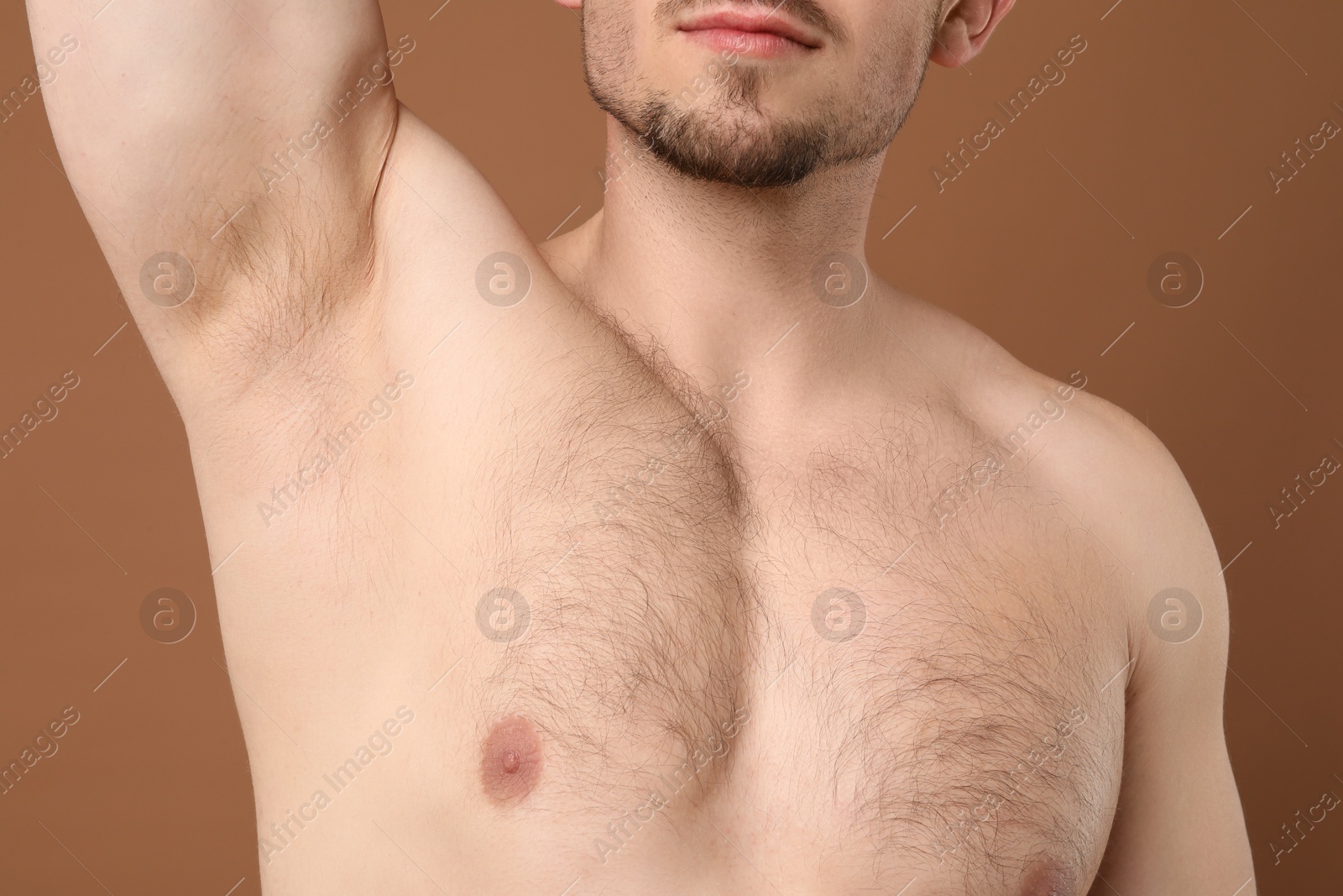 Young man showing hairy armpit on brown background, closeup. Epilation procedure Photo of Young man showing hairy armpit on brown background, closeup. Epilation procedure