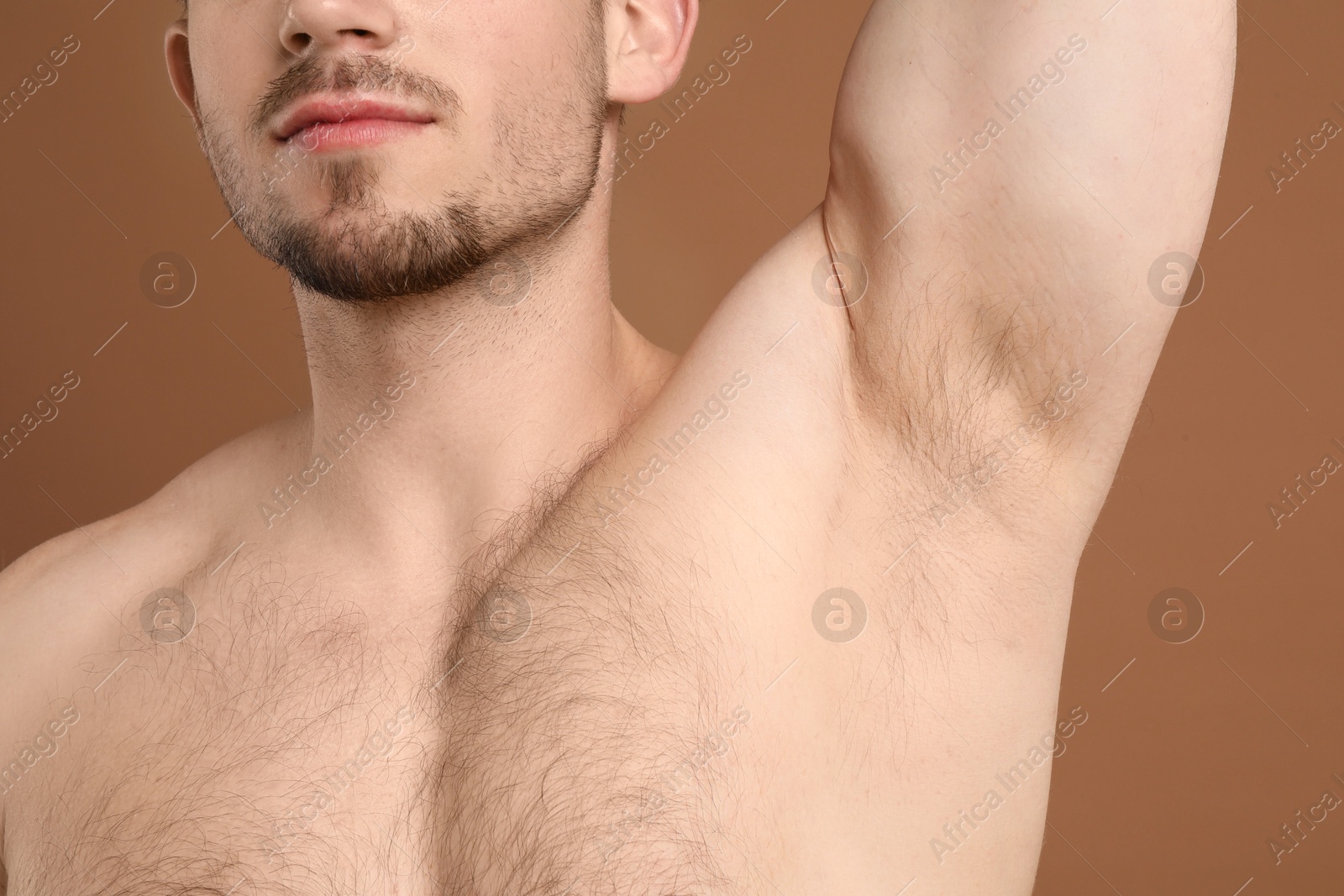 Young man showing hairy armpit on brown background, closeup. Epilation procedure Photo of Young man showing hairy armpit on brown background, closeup. Epilation procedure