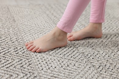 Photo of Girl walking on grey carpet at home, closeup