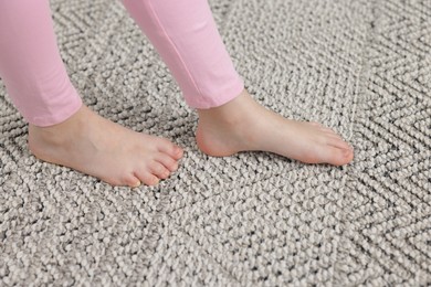 Photo of Girl walking on grey carpet at home, closeup