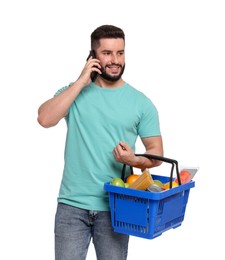 Photo of Man with shopping basket full of products talking on smartphone against white background