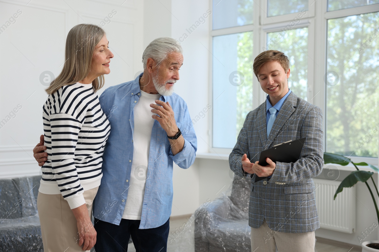 Smiling real estate agent with clipboard working with couple at home Photo of Smiling real estate agent with clipboard working with couple at home