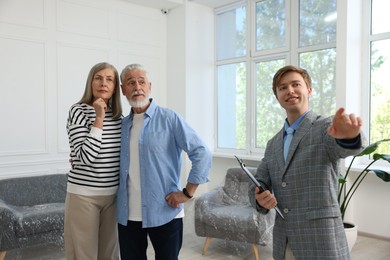 Photo of Smiling real estate agent showing apartment to couple indoors