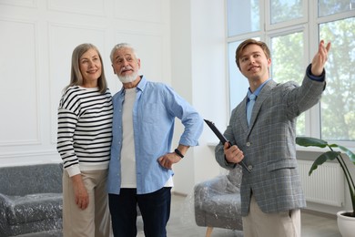 Photo of Smiling real estate agent showing apartment to couple indoors