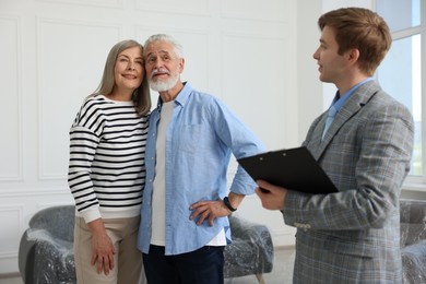 Photo of Real estate agent with clipboard and happy couple at home