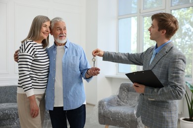 Photo of Smiling real estate agent giving house key to new owner at home