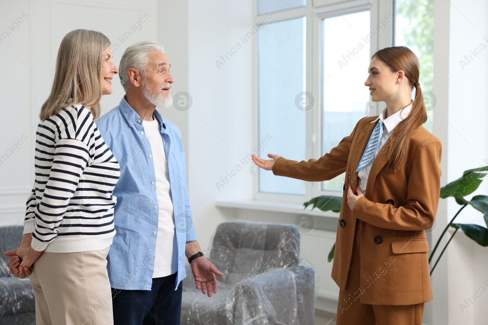 Smiling real estate agent showing apartment to couple indoors Photo of Smiling real estate agent showing apartment to couple indoors