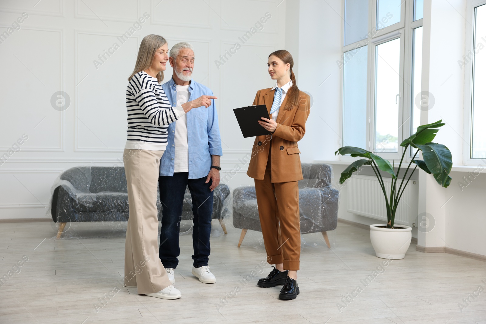 Smiling real estate agent with clipboard working with couple at home Photo of Smiling real estate agent with clipboard working with couple at home