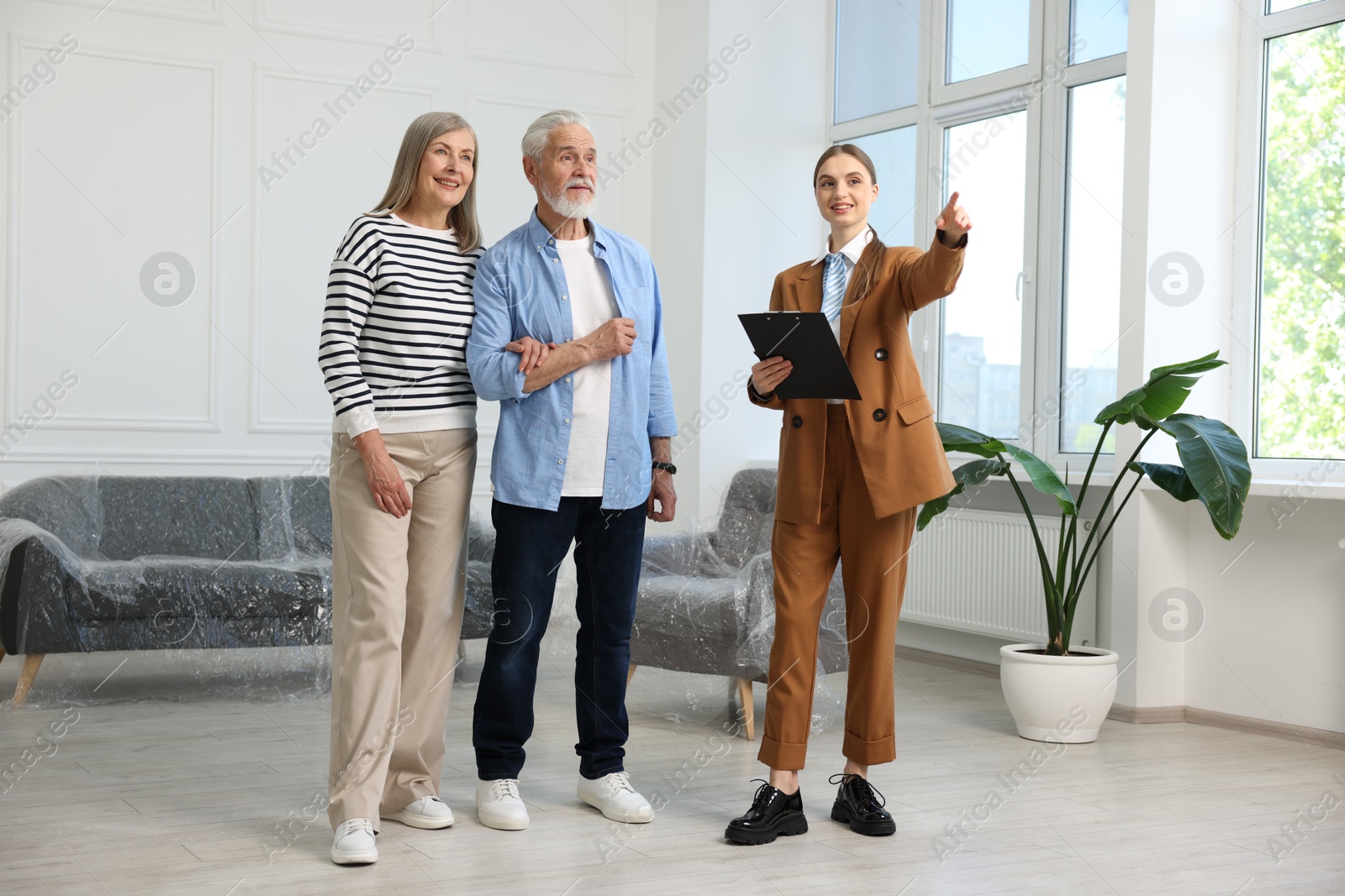 Smiling real estate agent showing apartment to couple indoors Photo of Smiling real estate agent showing apartment to couple indoors