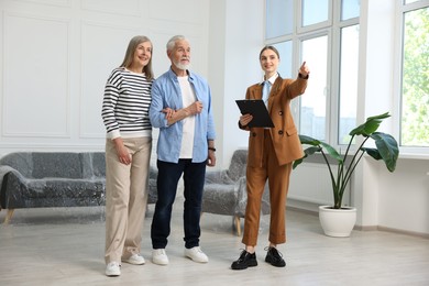 Photo of Smiling real estate agent showing apartment to couple indoors
