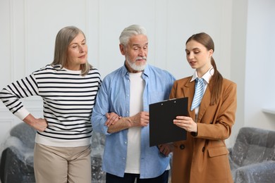 Photo of Real estate agent with clipboard working with couple at home