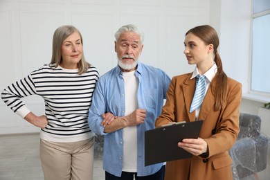 Photo of Real estate agent with clipboard working with couple at home