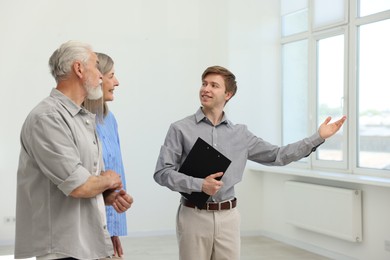 Photo of Smiling real estate agent showing apartment to couple indoors