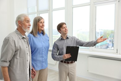 Photo of Smiling real estate agent showing apartment to couple indoors