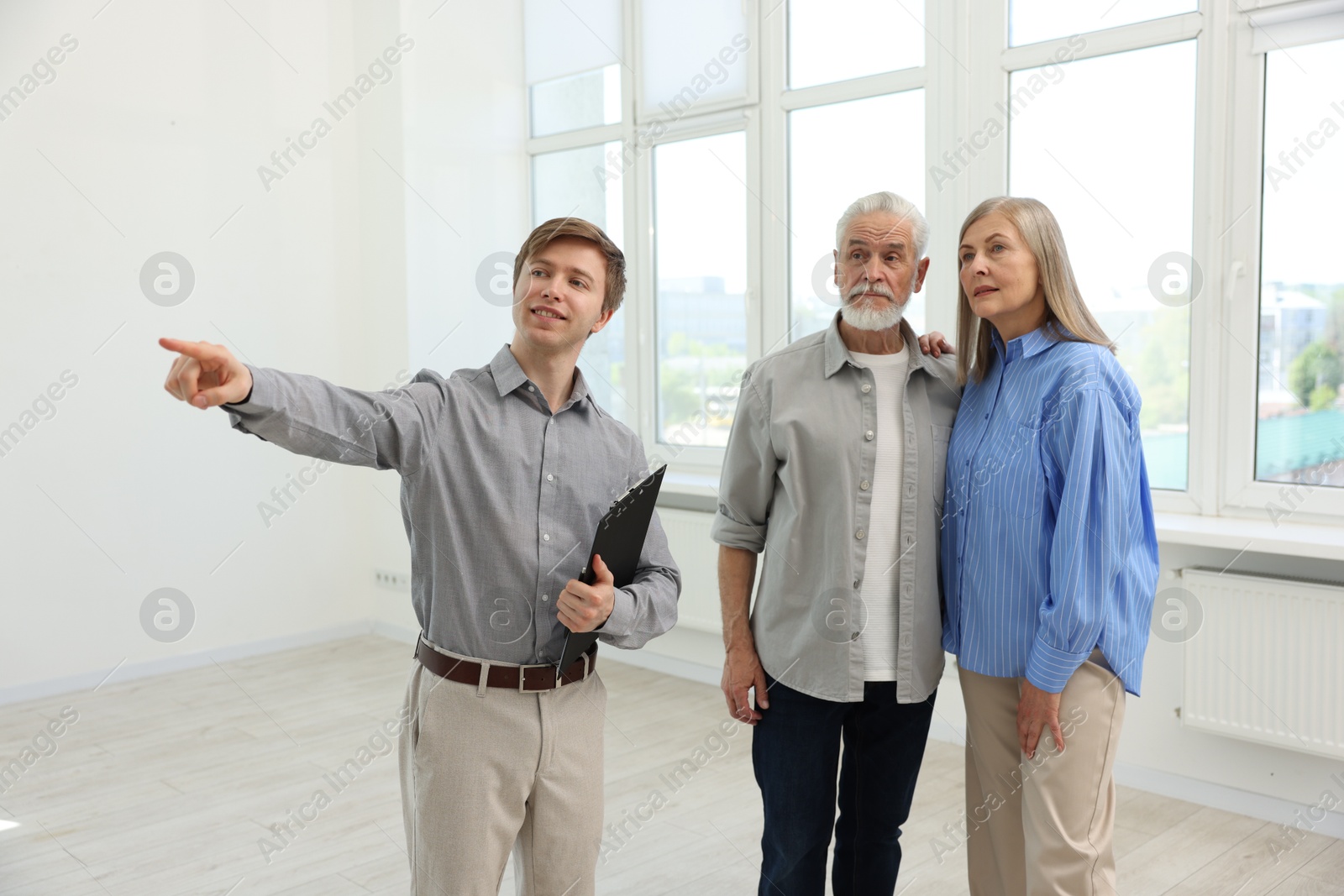 Smiling real estate agent showing apartment to couple indoors Photo of Smiling real estate agent showing apartment to couple indoors