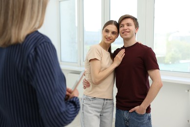 Photo of Real estate agent and young couple at home, selective focus