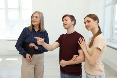Photo of Smiling real estate agent working with couple at home
