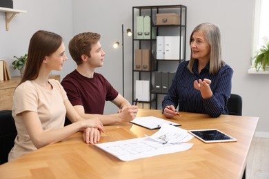 Photo of Smiling real estate agent working with couple at table in office
