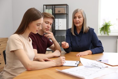 Photo of Real estate agent working with couple at table in office