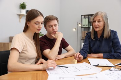 Photo of Real estate agent working with couple at table in office