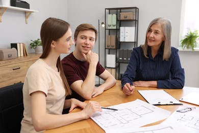 Photo of Smiling real estate agent working with couple at table in office
