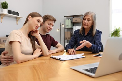 Photo of Real estate agent working with couple at table in office