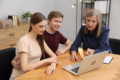 Photo of Real estate agent working with couple at table in office