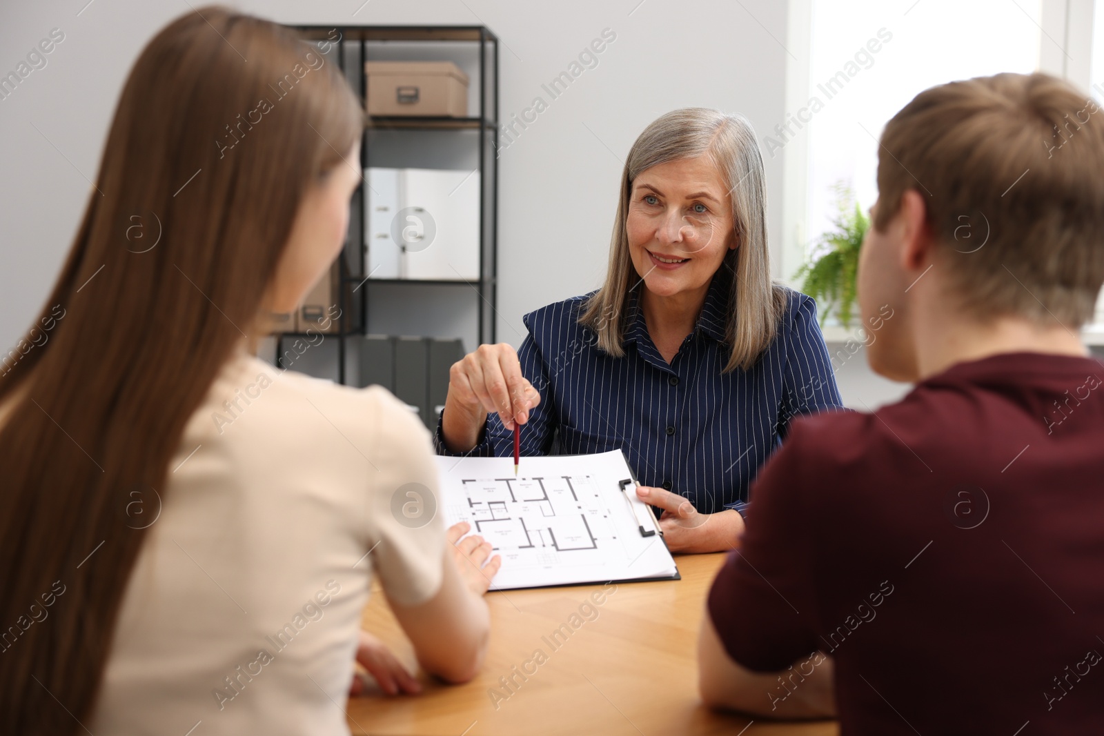 Smiling real estate agent working with couple at table in office Photo of Smiling real estate agent working with couple at table in office