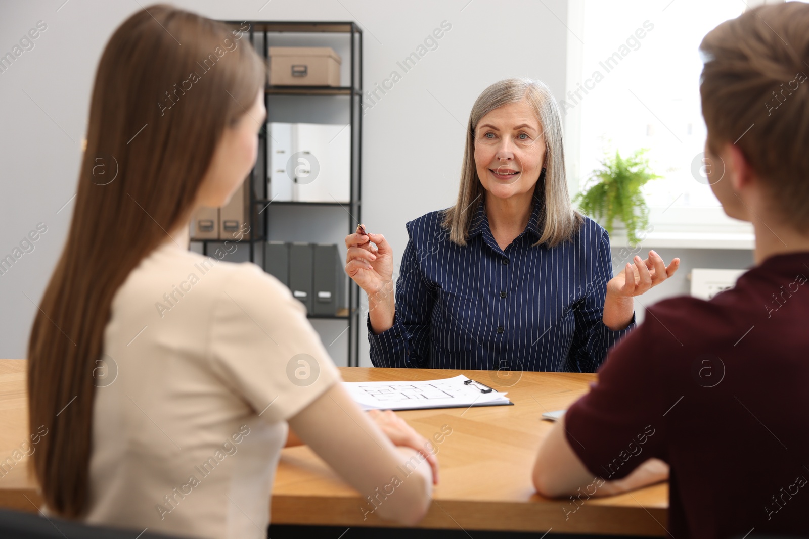 Smiling real estate agent working with couple at table in office Photo of Smiling real estate agent working with couple at table in office