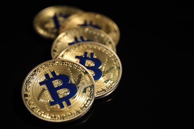 Photo of Cryptocurrency. Bitcoins on black mirror surface, closeup. Space for text