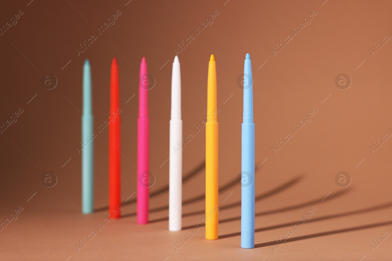 Colorful twist up eye pencils on beige background, closeup Photo of Colorful twist up eye pencils on beige background, closeup