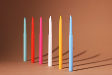 Photo of Colorful twist up eye pencils on beige background, closeup