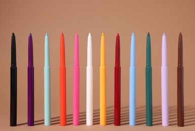 Photo of Colorful twist up eye pencils on beige background, closeup