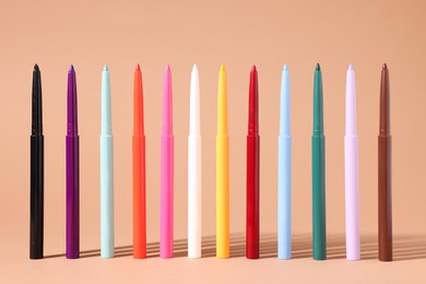 Photo of Colorful twist up eye pencils on beige background, closeup