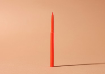 Photo of One twist up eye pencil on beige background, closeup
