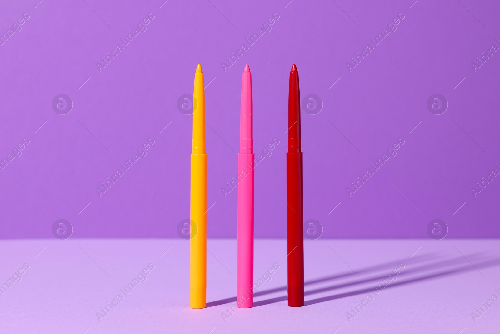 Colorful twist up eye pencils on purple background, closeup Photo of Colorful twist up eye pencils on purple background, closeup