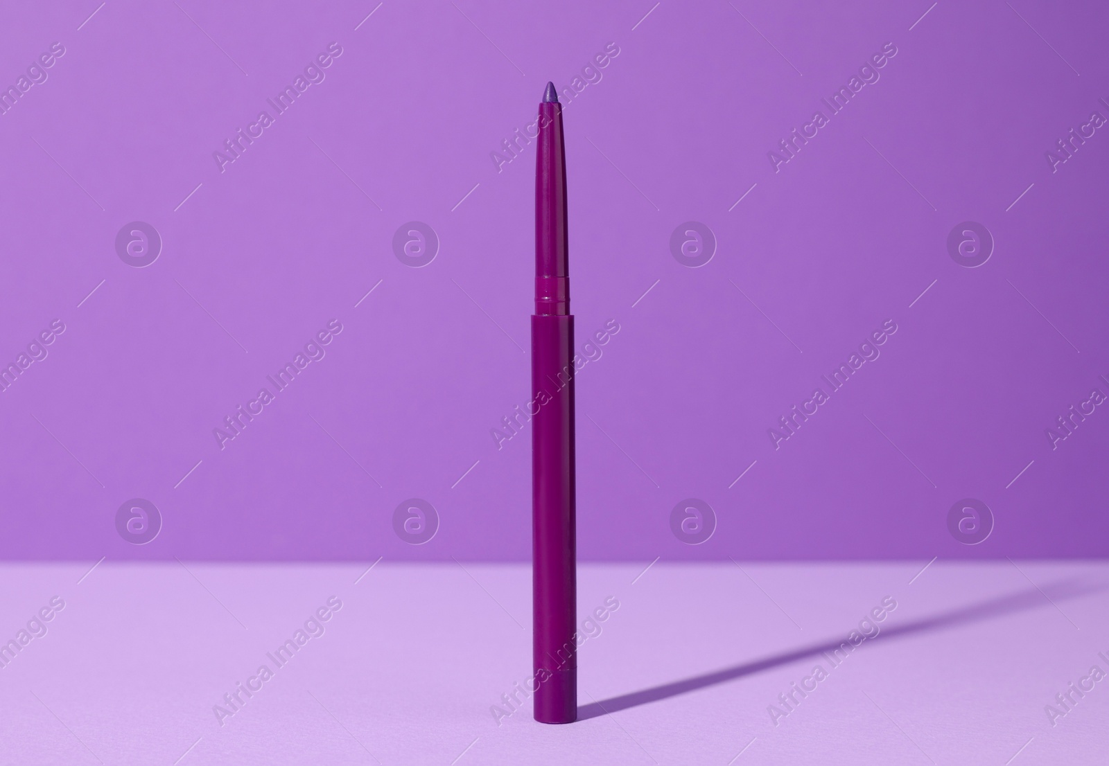 One twist up eye pencil on purple background, closeup Photo of One twist up eye pencil on purple background, closeup