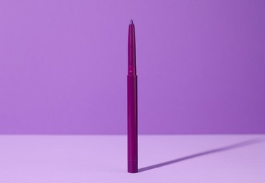 Photo of One twist up eye pencil on purple background, closeup