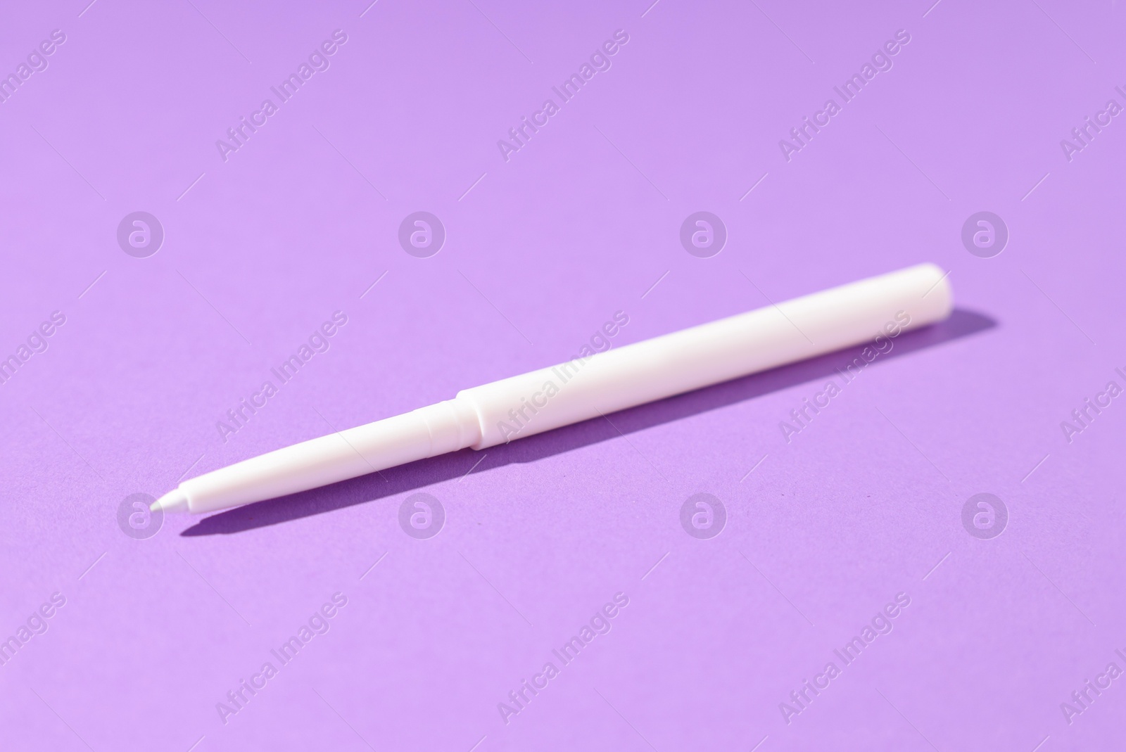 One twist up eye pencil on purple background, closeup Photo of One twist up eye pencil on purple background, closeup