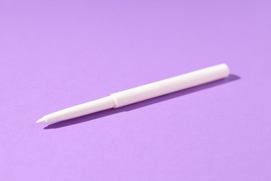Photo of One twist up eye pencil on purple background, closeup