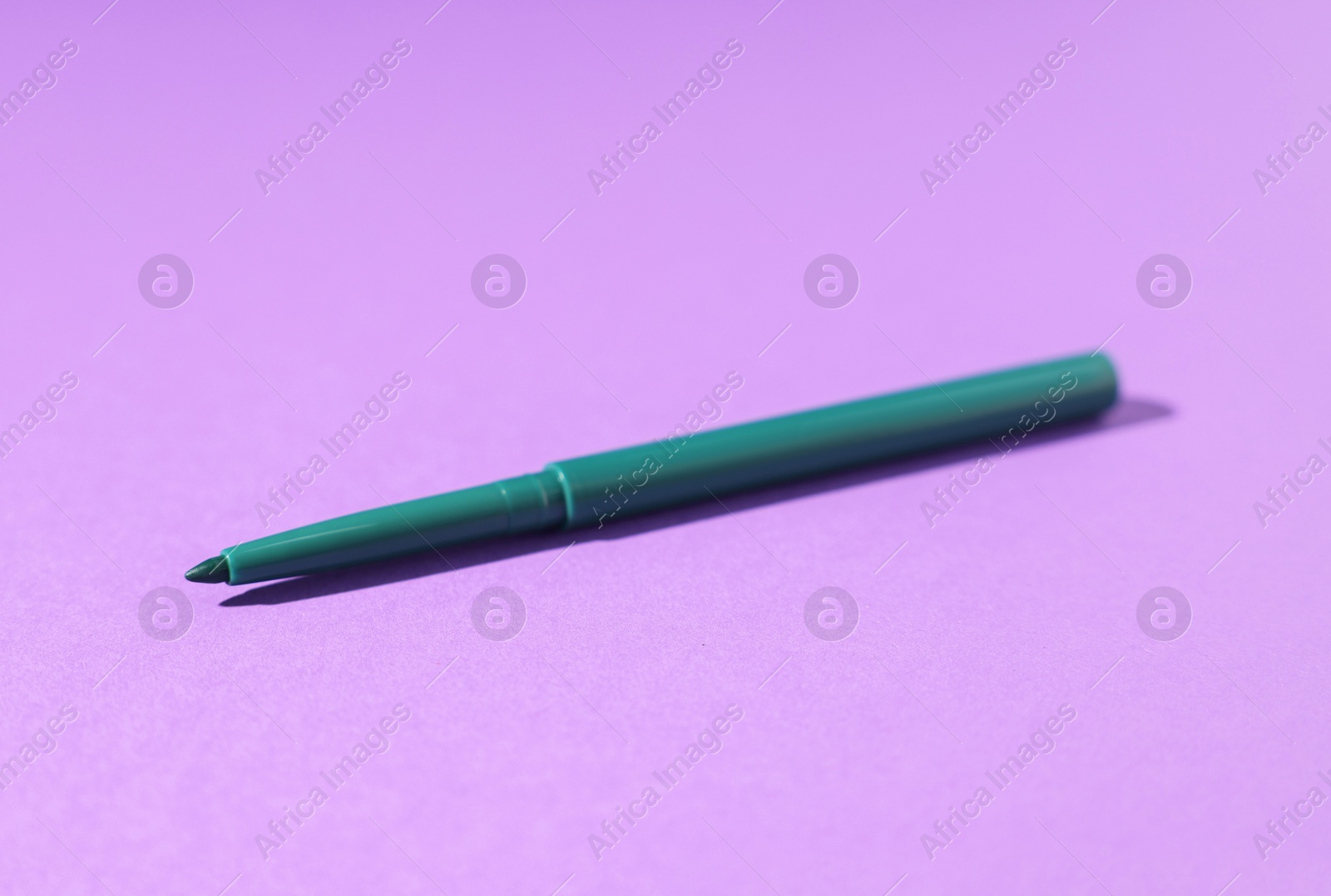 One twist up eye pencil on purple background, closeup Photo of One twist up eye pencil on purple background, closeup