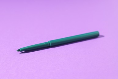 Photo of One twist up eye pencil on purple background, closeup