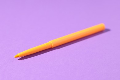 Photo of One twist up eye pencil on purple background, closeup